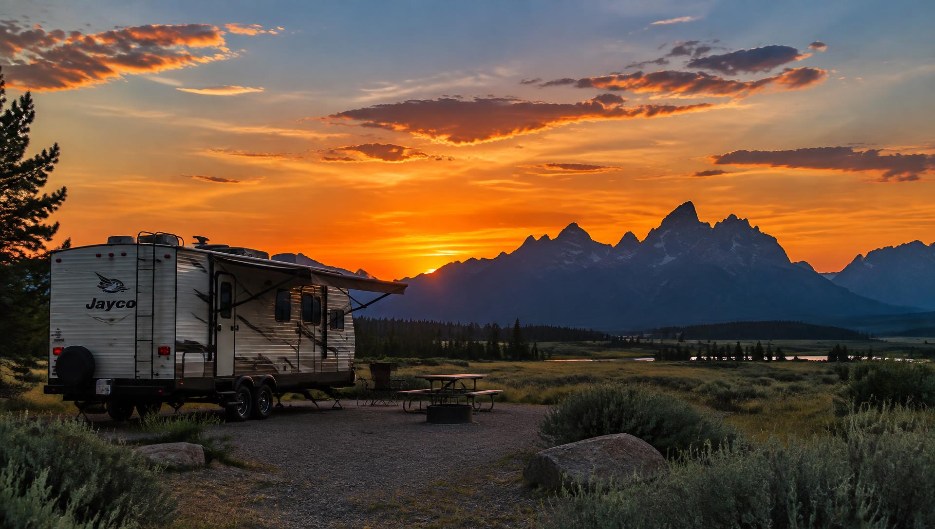 Travel trailer at a Wyoming campground with mountains at sunset